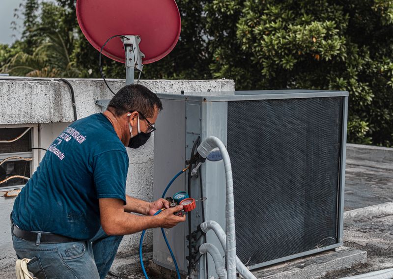 A technician kneels outdoors, performing HVAC maintenance using specialized tools, enhancing system performance.